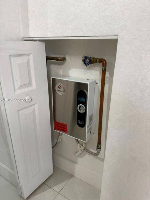 Wall-mounted tankless electric water heater featuring a digital control panel and stainless steel finish, enclosed within a recessed utility cabinet