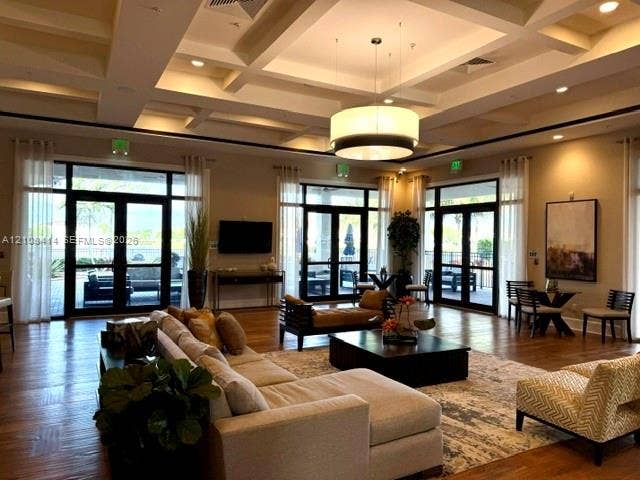 Coffered ceiling, wood-finish flooring, recessed lighting, large drum pendant light, and multiple sets of glass-paned double doors
