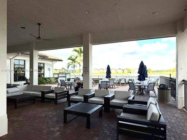 Covered outdoor terrace featuring paver flooring, support columns, recessed lighting, and a ceiling fan