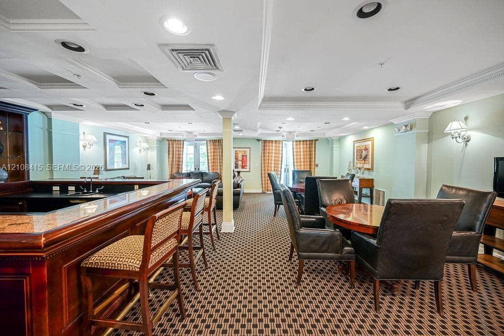 1900 Van Buren Street, #303B, Hollywood, Hollywood, FL 33020 Custom wet bar featuring wood cabinetry and stone-surface countertop, coffered ceiling with recessed lighting, and wall-mounted sconce fixtures