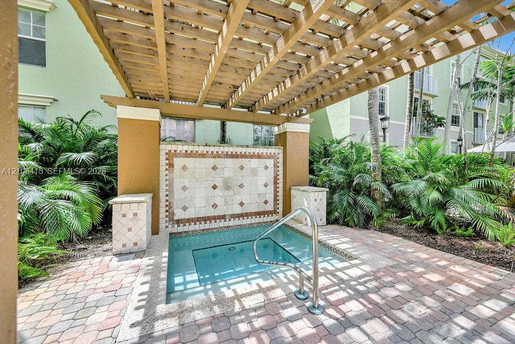 1900 Van Buren Street, #303B, Hollywood, Hollywood, FL 33020 Outdoor spa featuring a concrete paver deck, a wood-beam pergola, decorative tile masonry, and integrated metal handrail