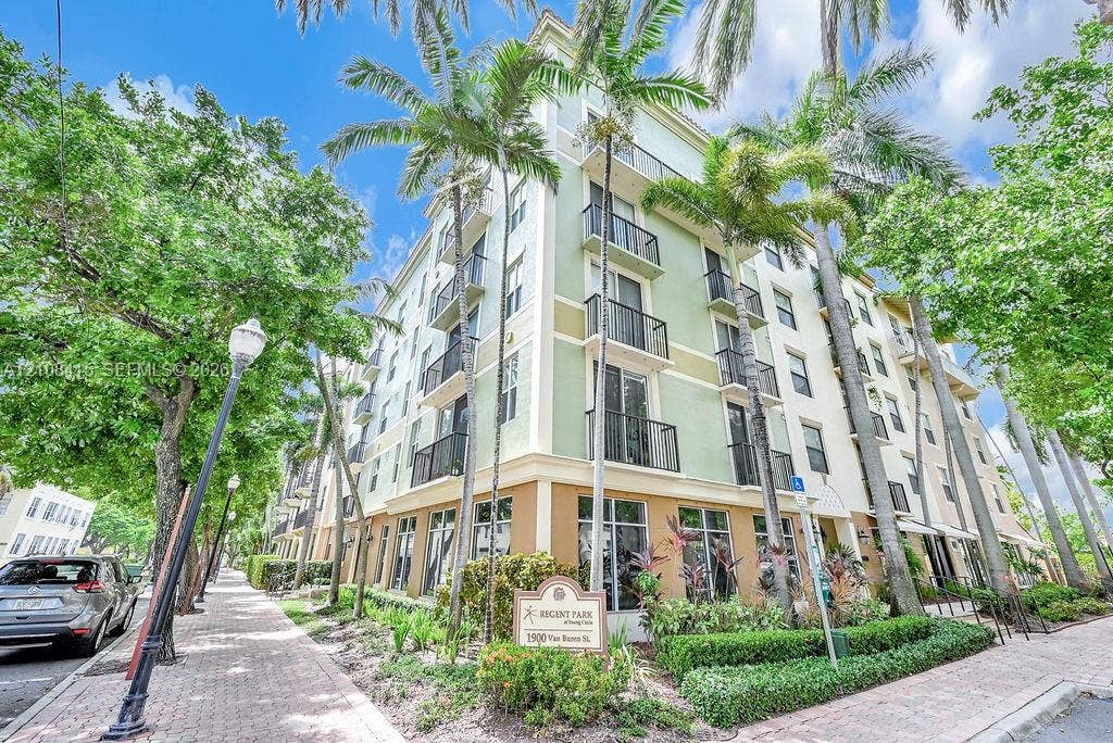 1900 Van Buren Street, #303B, Hollywood, Hollywood, FL 33020 Multi-story building exterior featuring a stucco facade, metal balcony railings, floor-to-ceiling windows, and surrounding palm tree landscaping