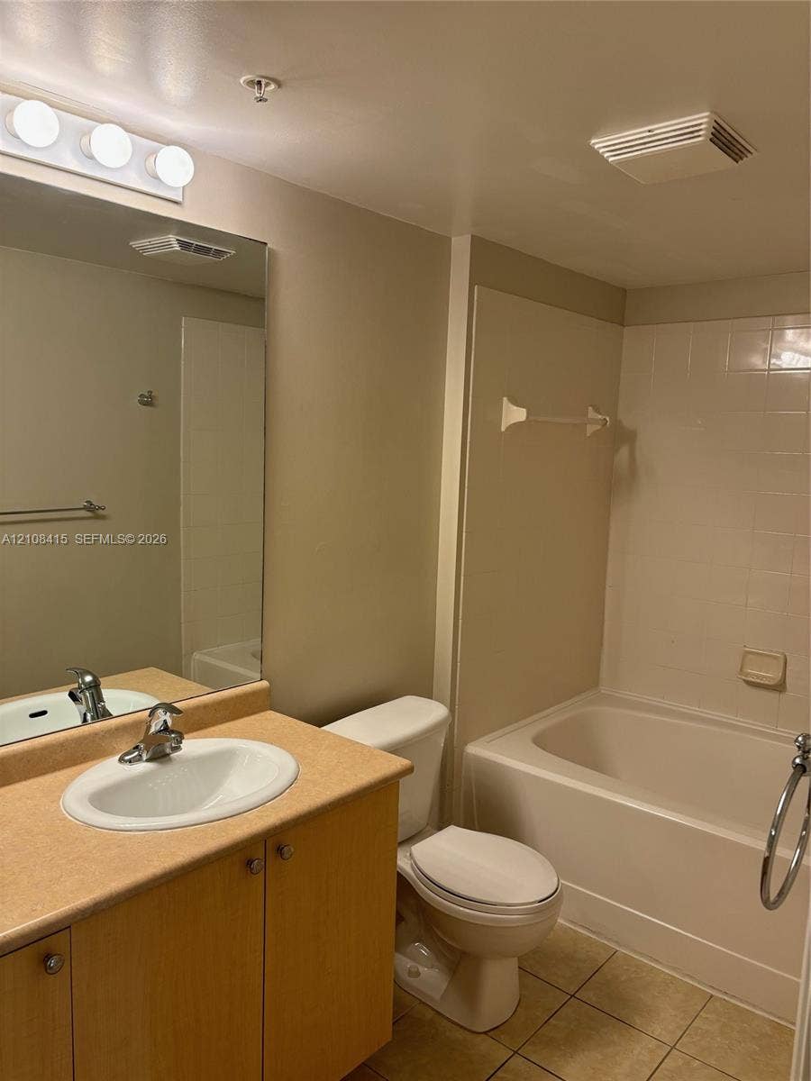 1900 Van Buren Street, #303B, Hollywood, Hollywood, FL 33020 Bathroom featuring a vanity with a solid-surface countertop, an integrated oval basin, light wood-finish cabinetry, a large wall-mounted mirror, and a tiled tub-shower combination