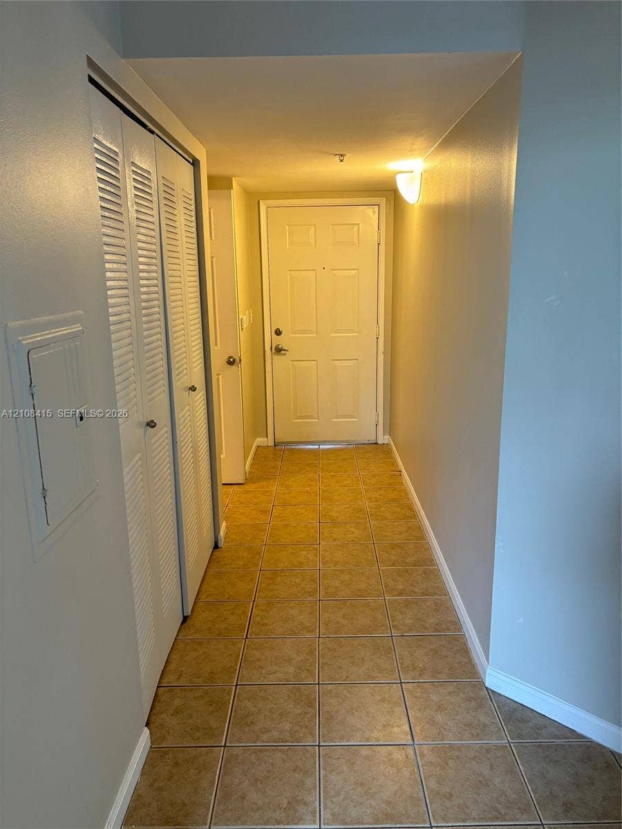 1900 Van Buren Street, #303B, Hollywood, Hollywood, FL 33020 Interior hallway featuring tile flooring, louvered-style closet doors, and wall-mounted lighting