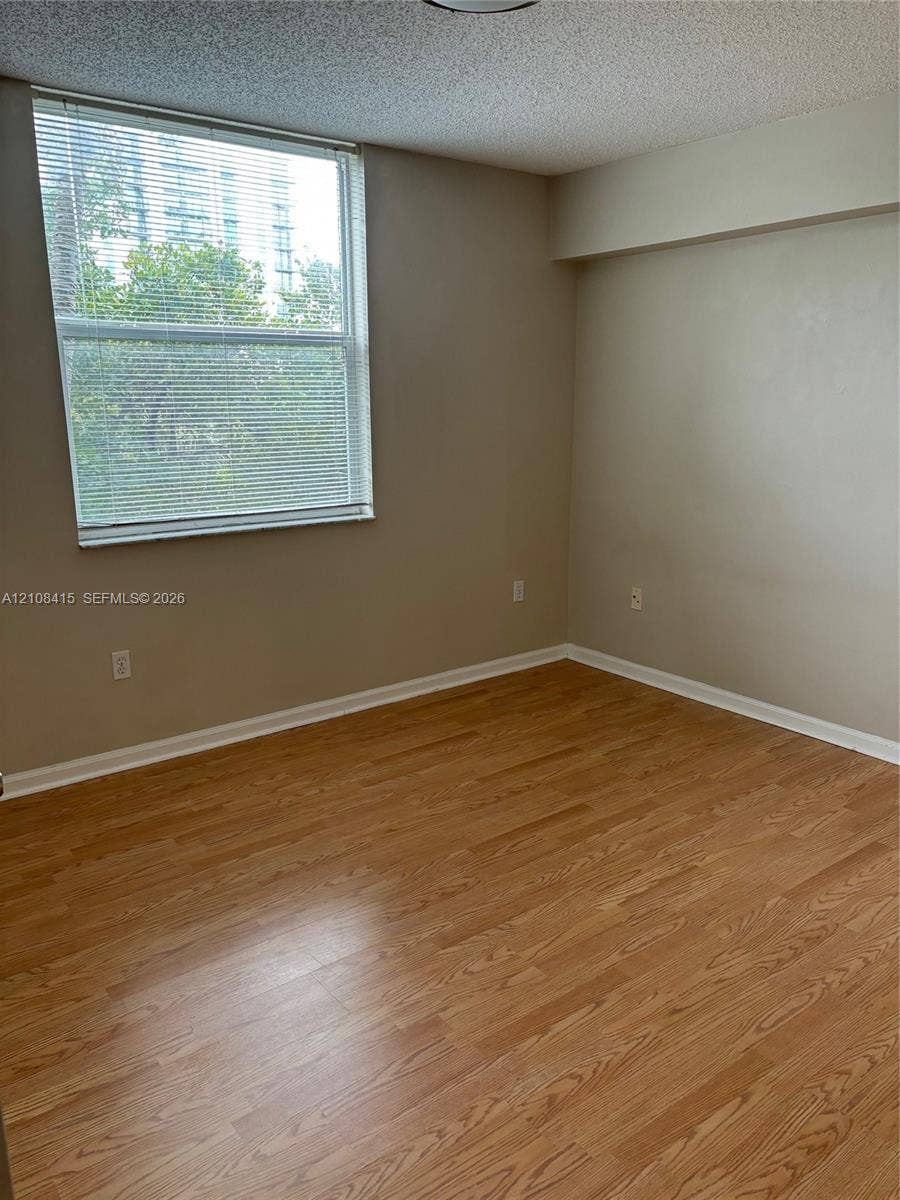 1900 Van Buren Street, #303B, Hollywood, Hollywood, FL 33020 Room featuring wood-finish flooring, neutral wall paint, and a large window with horizontal blinds