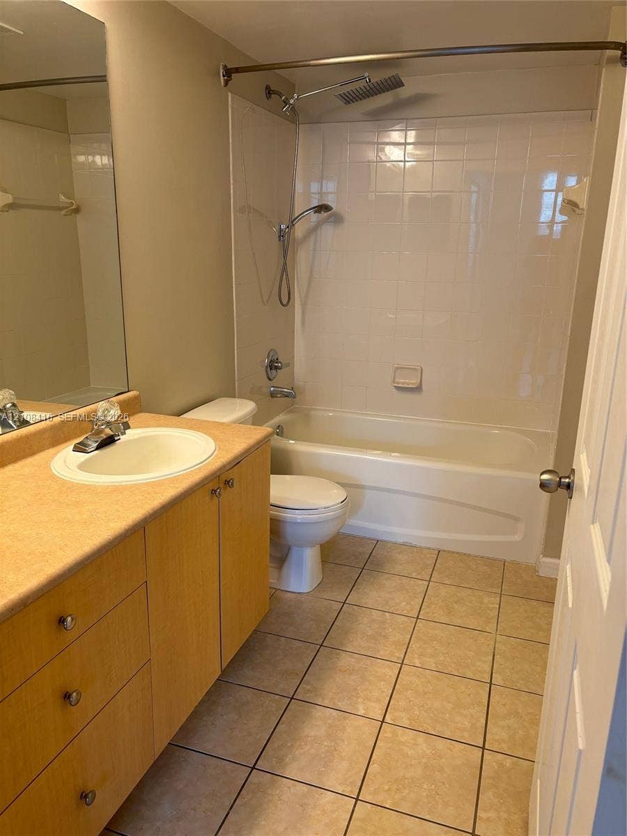 1900 Van Buren Street, #303B, Hollywood, Hollywood, FL 33020 Bathroom featuring wood-finish cabinetry, a drop-in sink, ceramic tile flooring, a shower-tub combination with tile surround, and a handheld showerhead