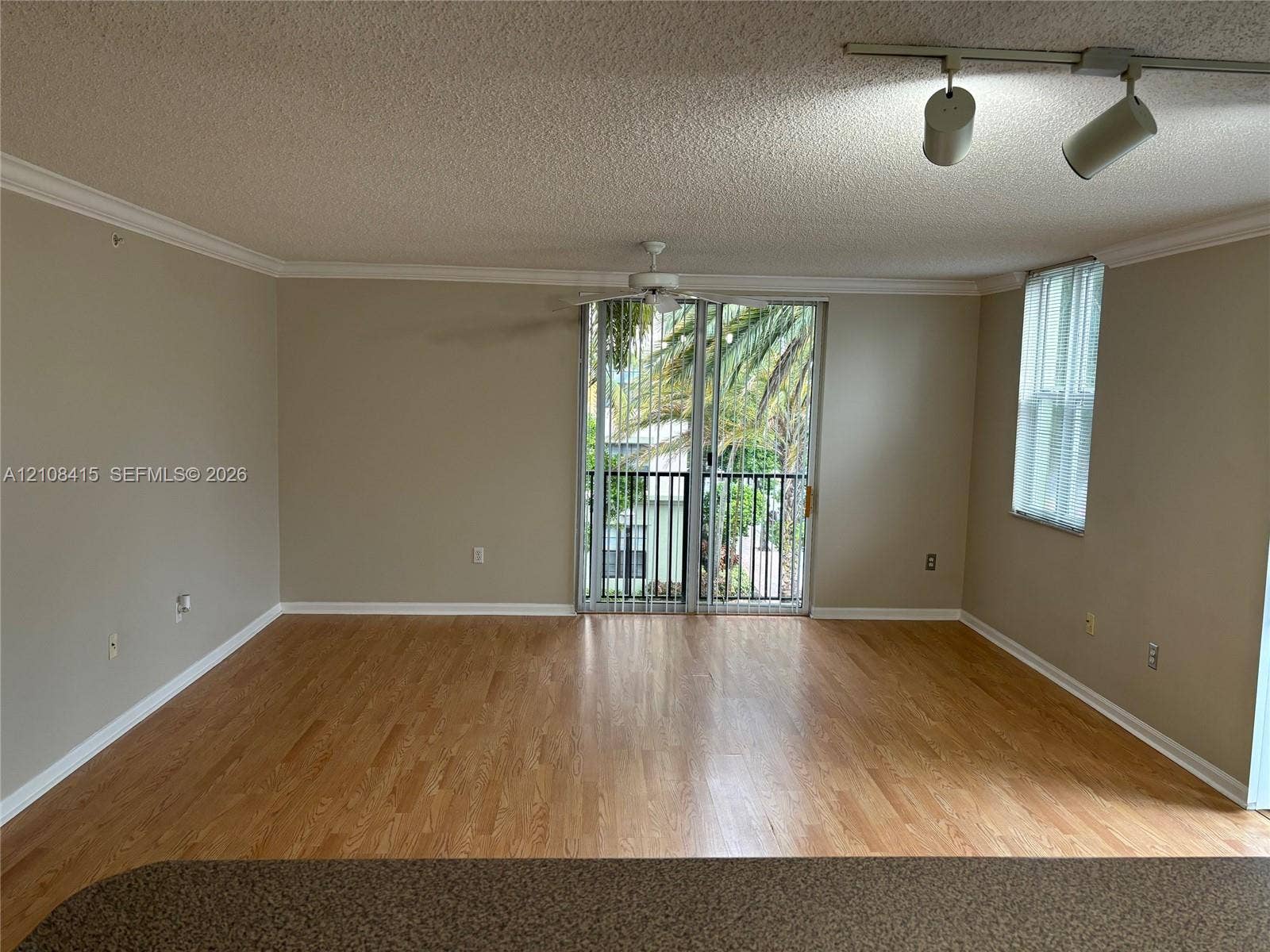 1900 Van Buren Street, #303B, Hollywood, Hollywood, FL 33020 Living area featuring wood-finish flooring, crown molding, sliding glass door with balcony access, ceiling fan, and adjustable track lighting