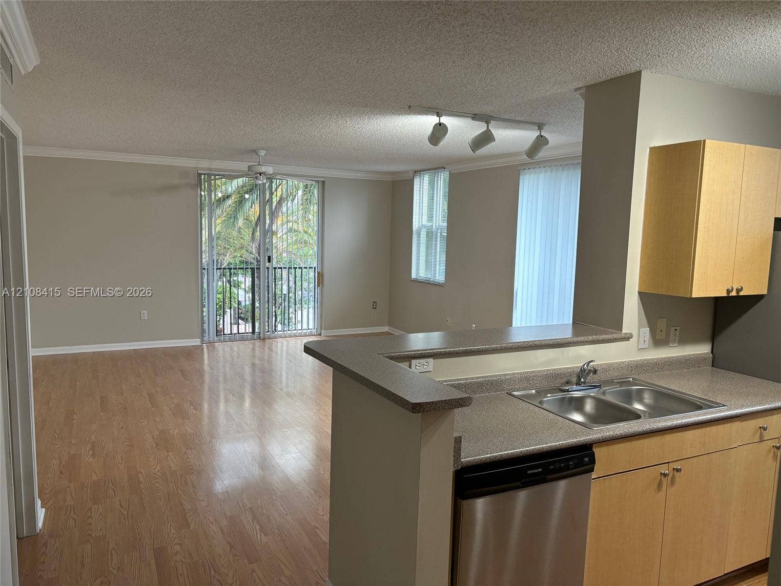 1900 Van Buren Street, #303B, Hollywood, Hollywood, FL 33020 Open-concept interior featuring wood-finish flooring, a breakfast bar, stainless steel dishwasher, light-finish cabinetry, and a sliding glass door