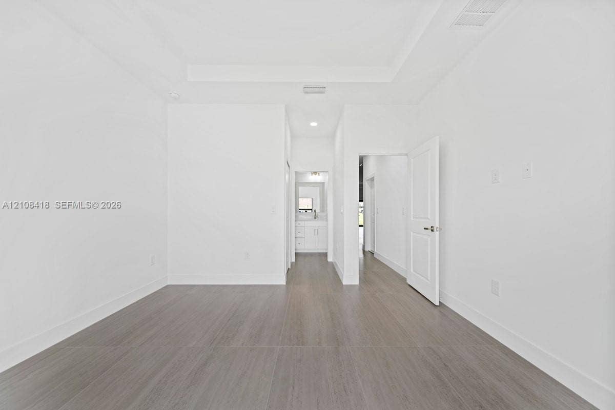 2235 Wayne Avenue S, Lehigh Acres, FL 33973 Tray ceiling, wood-finish flooring, recessed lighting, and white multi-panel interior door