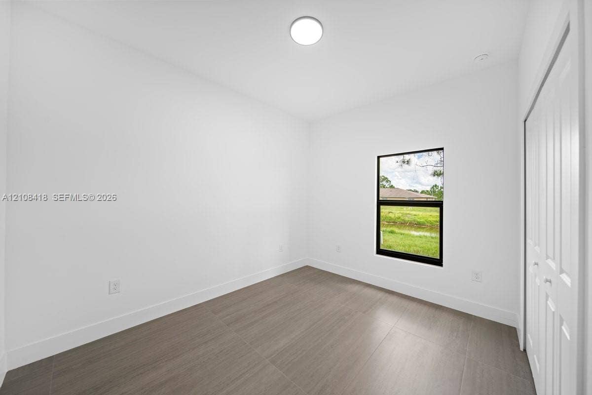 2235 Wayne Avenue S, Lehigh Acres, FL 33973 Neutral interior featuring wood-finish flooring, a flush-mount ceiling light, a single window with a black frame, and a bi-fold closet door