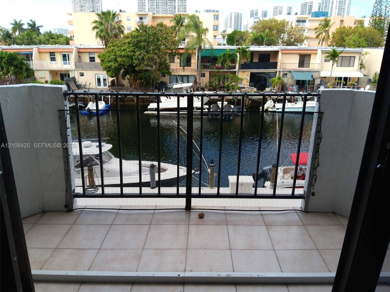 3545 NE 166th Street, #306, North Miami Beach, FL 33160 Private balcony featuring neutral ceramic tile flooring and a black metal railing overlooking a deep-water canal