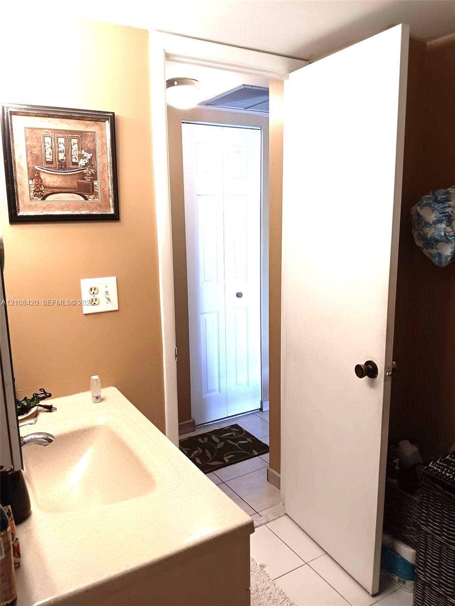3545 NE 166th Street, #306, North Miami Beach, FL 33160 Integrated vanity featuring a solid surface countertop with an oval-inset basin and neutral tile flooring