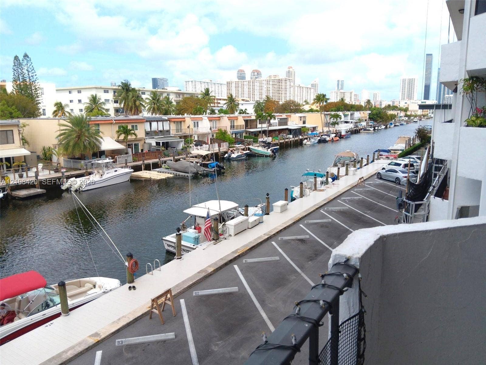 3545 NE 166th Street, #306, North Miami Beach, FL 33160 Elevated balcony overlooking a concrete dock featuring assigned parking spaces and direct waterway access