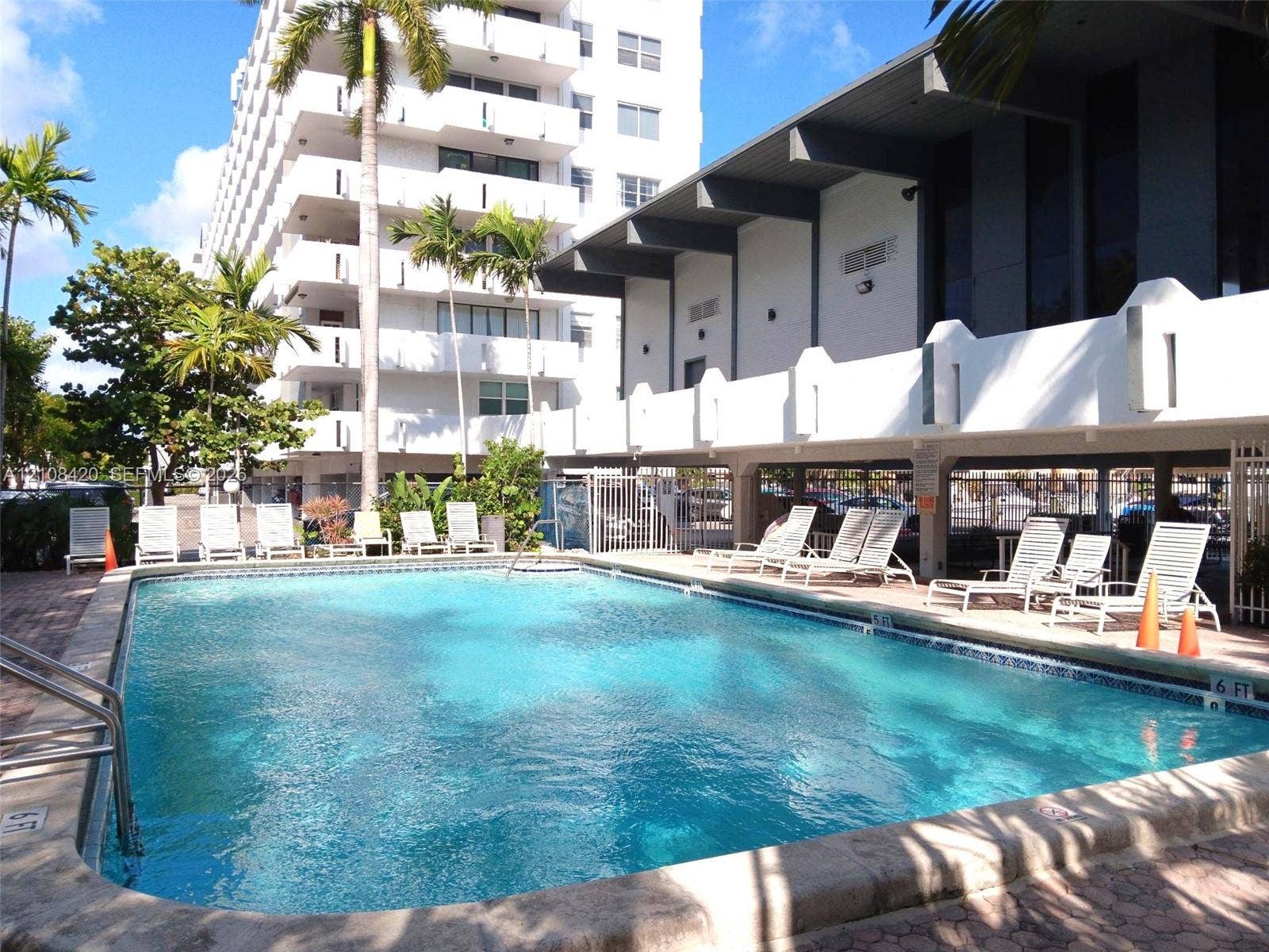 3545 NE 166th Street, #306, North Miami Beach, FL 33160 Swimming pool with concrete decking, metal handrails, and surrounding landscaping