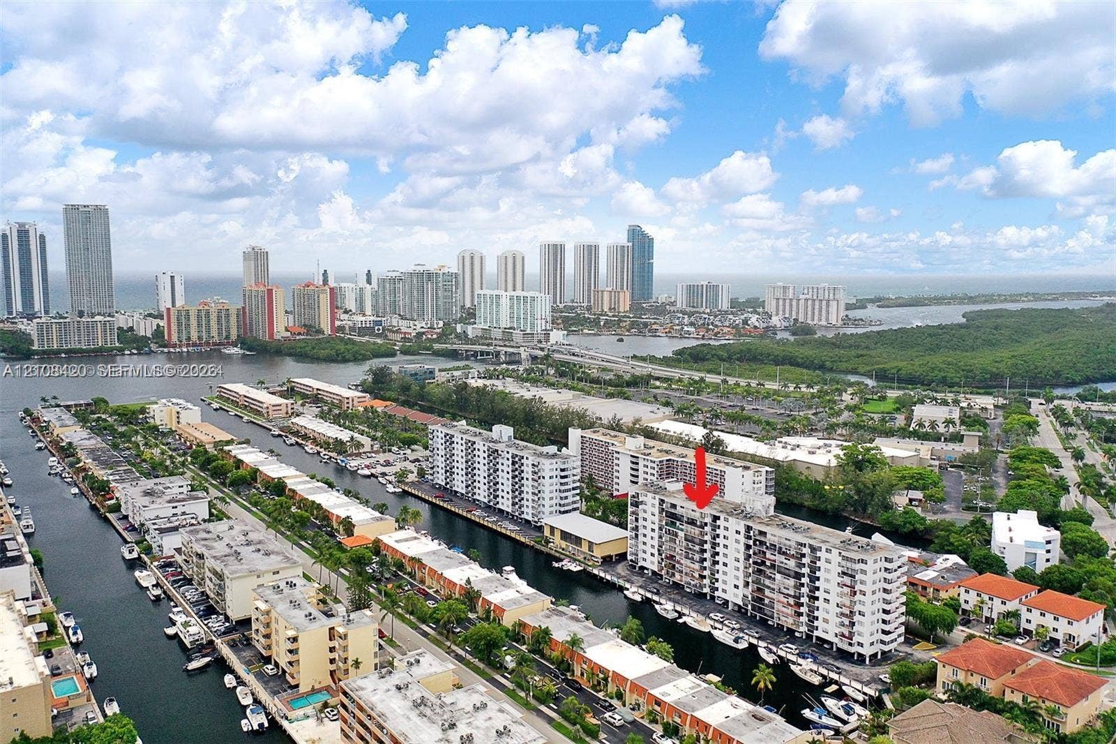 3545 NE 166th Street, #306, North Miami Beach, FL 33160 Aerial perspective of a high-rise residential building featuring waterfront positioning, private balconies, and proximity to coastal waterways