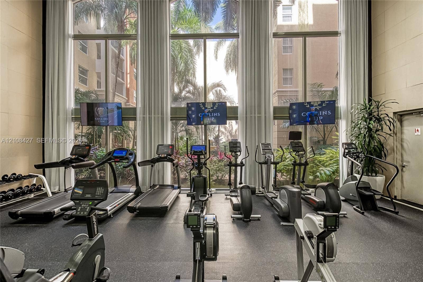 Fitness center featuring floor-to-ceiling windows, high ceilings, and rubberized flooring