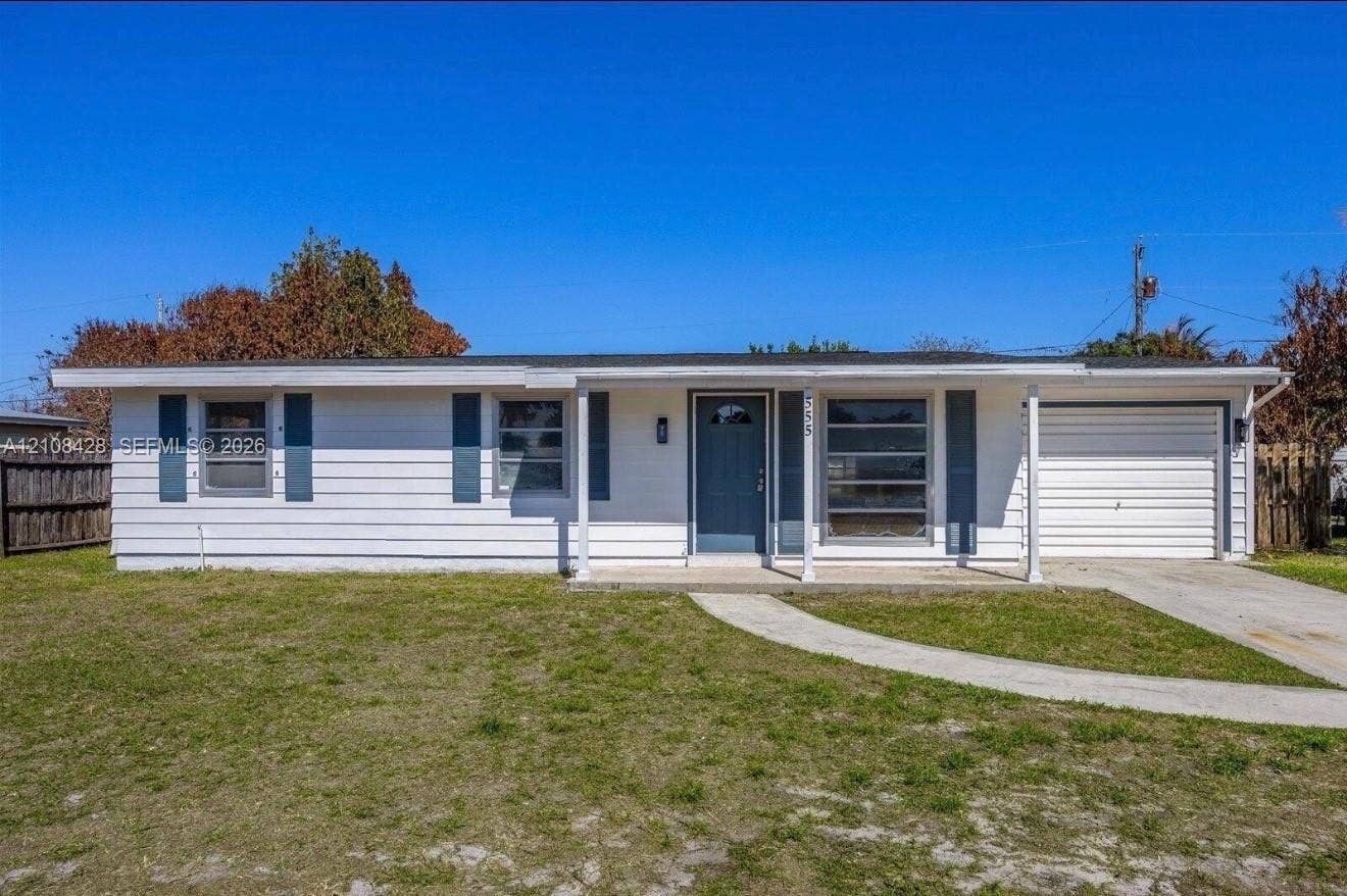 555 SE Airoso Boulevard, Port St Lucie, Port St Lucie, FL 34983 Single-story exterior featuring white horizontal siding, contrasting shutters, an attached one-car garage, and a covered front entry