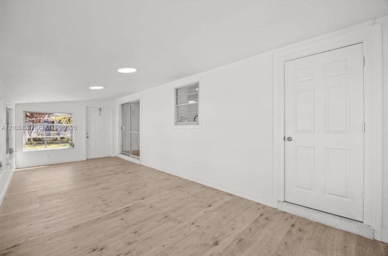 555 SE Airoso Boulevard, Port St Lucie, Port St Lucie, FL 34983 Room featuring wood-finish flooring, two recessed ceiling lights, a glass sliding door, and multiple exterior access doors