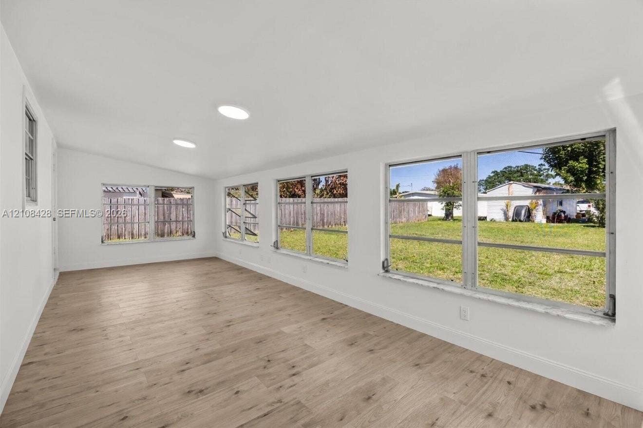 555 SE Airoso Boulevard, Port St Lucie, Port St Lucie, FL 34983 Open-concept interior featuring light wood-finish flooring, recessed lighting, and multiple horizontal sliding windows providing natural illumination
