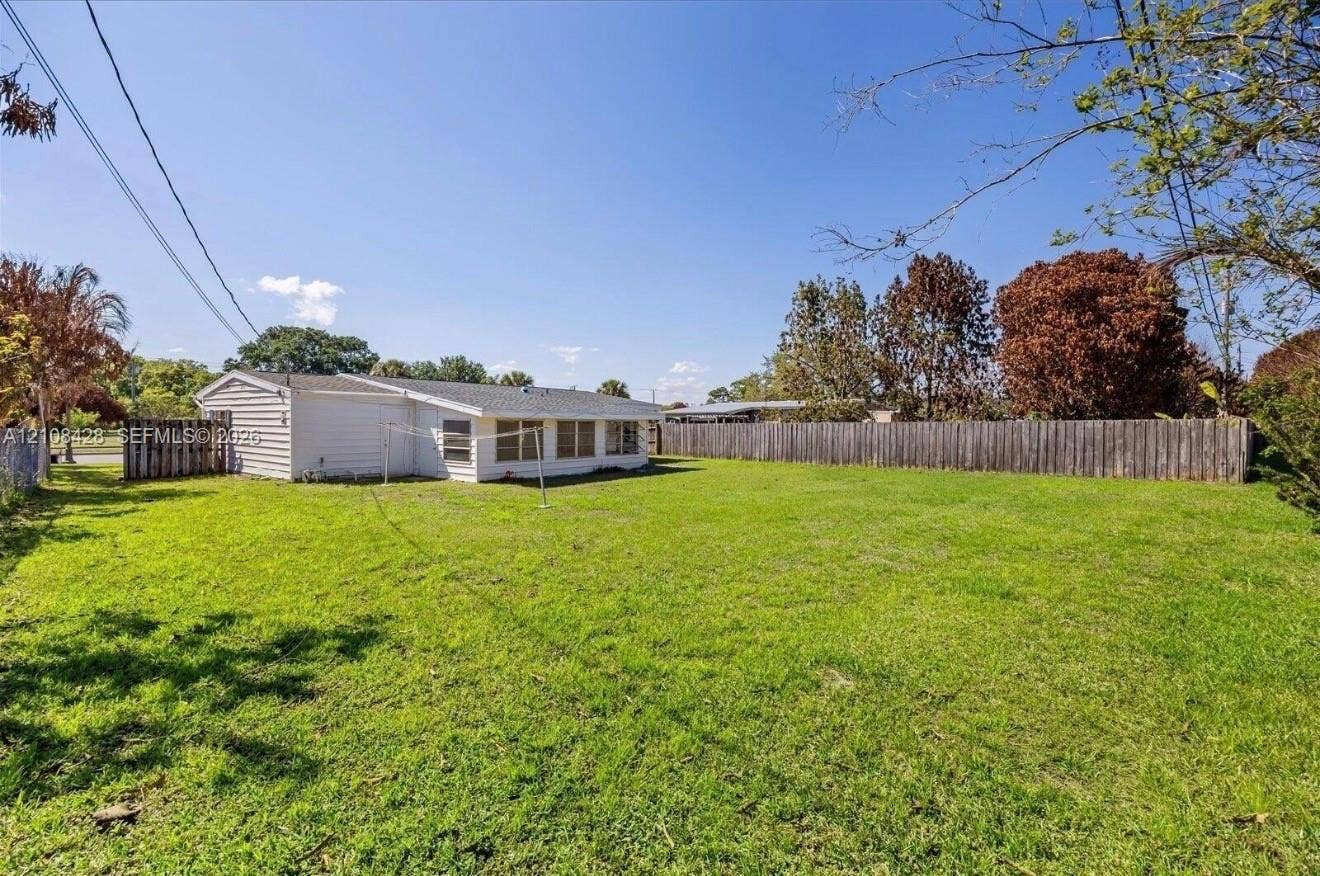 555 SE Airoso Boulevard, Port St Lucie, Port St Lucie, FL 34983 Expansive backyard featuring a large grass lawn and perimeter wood fencing