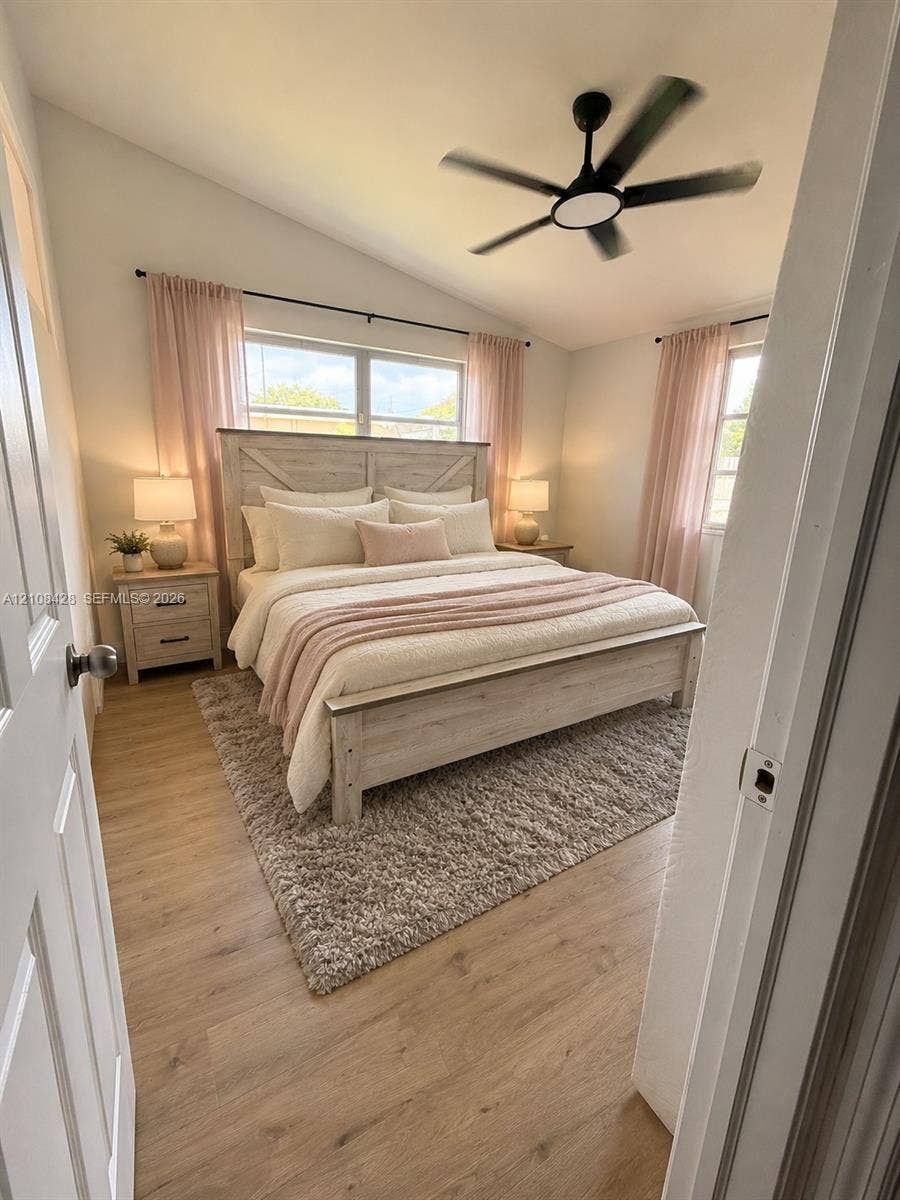 555 SE Airoso Boulevard, Port St Lucie, Port St Lucie, FL 34983 Vaulted ceilings, wood-finish flooring, dual windows with black curtain rods, and a multi-blade ceiling fan with integrated lighting