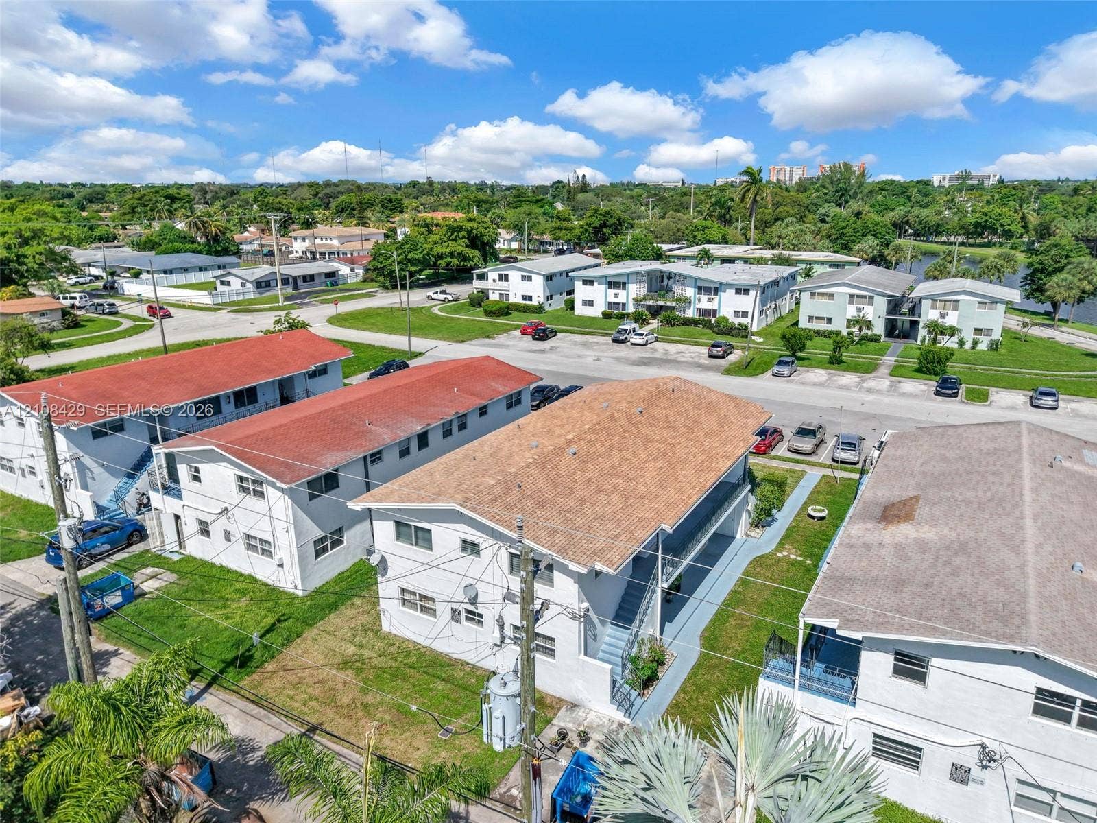 1430 NE 171st Street, North Miami Beach, FL 33162 Multi-unit residential complex featuring shingled roofs, exterior staircase access, and dedicated surface parking