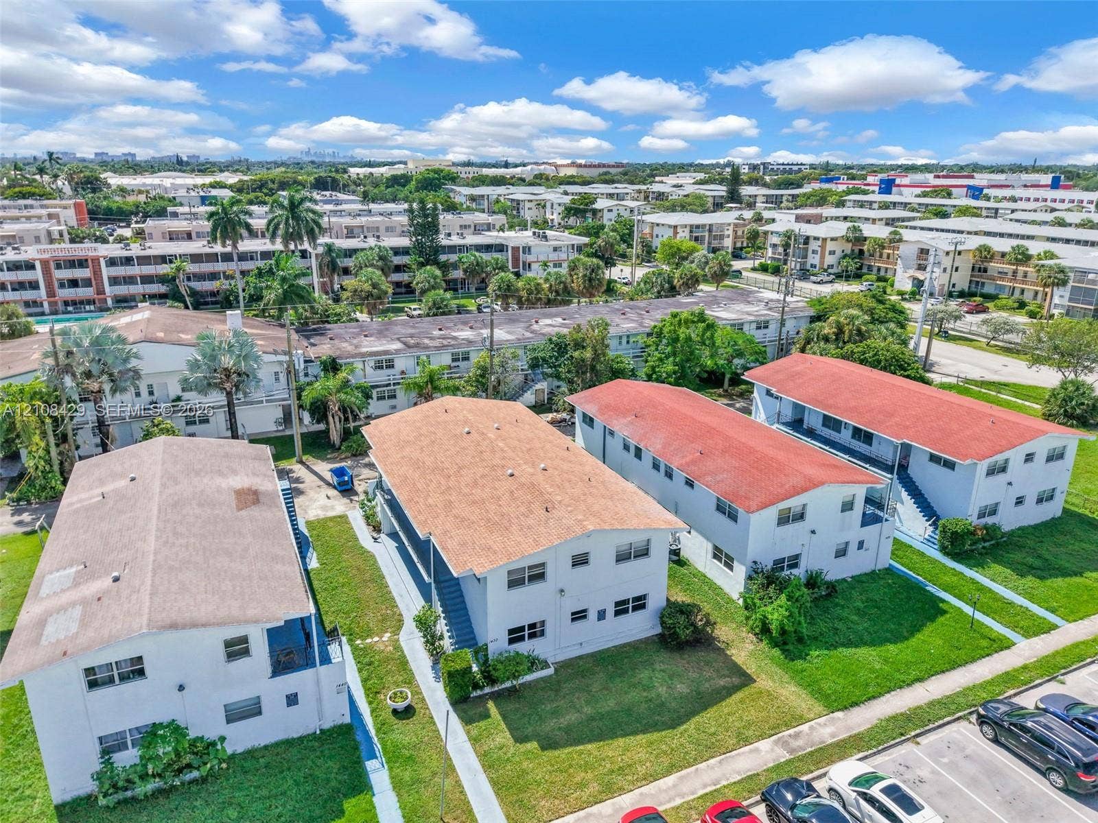 1430 NE 171st Street, North Miami Beach, FL 33162 Aerial view of multi-unit residential structures featuring white exteriors, gabled roofs with composition shingles, and integrated concrete walkways