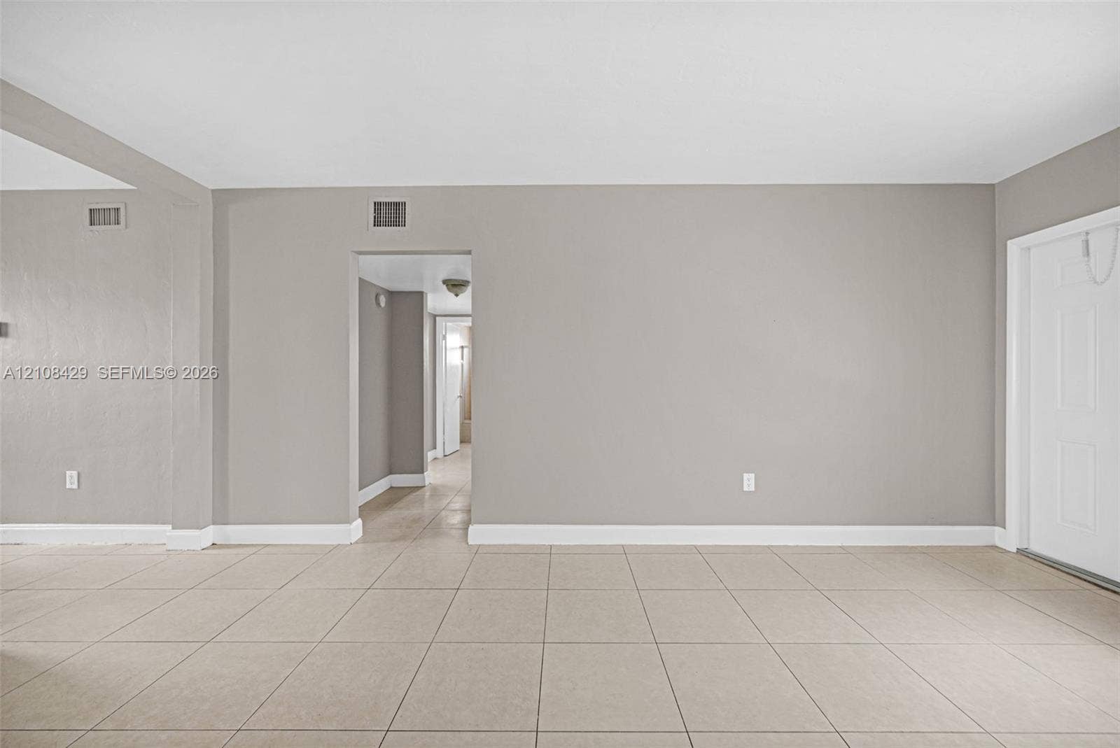 1430 NE 171st Street, North Miami Beach, FL 33162 Neutral-toned interior space featuring large-format ceramic tile flooring, solid-core interior doors, and a recessed doorway leading to an additional interior space