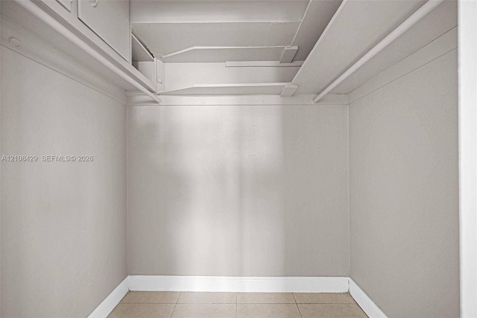 1430 NE 171st Street, North Miami Beach, FL 33162 Storage space featuring tiled flooring, built-in shelving, and dual hanging rods