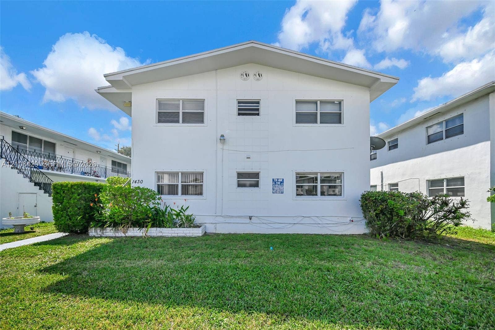 1430 NE 171st Street, North Miami Beach, FL 33162 Two-story exterior featuring a white stucco facade, a low-pitched gabled roofline, and multiple horizontal windows