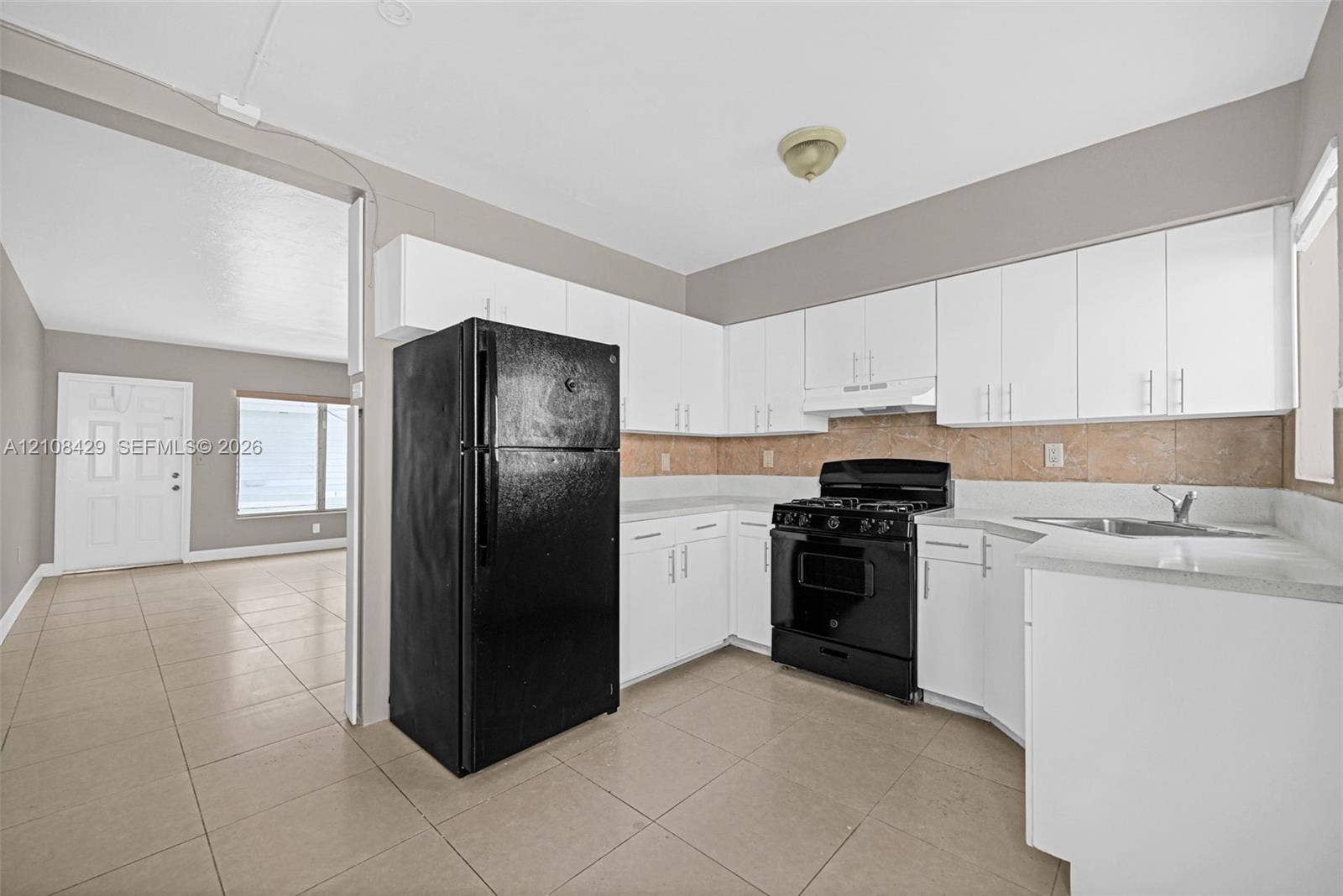 1430 NE 171st Street, North Miami Beach, FL 33162 Kitchen featuring white cabinetry, solid-surface countertops, stone-finish backsplash, and black appliances
