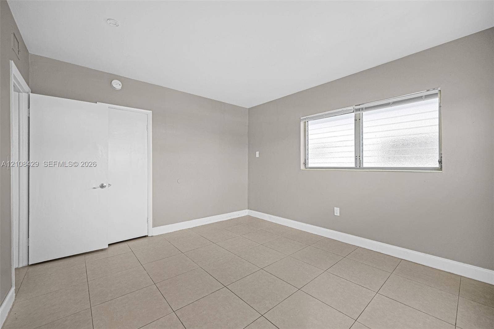 1430 NE 171st Street, North Miami Beach, FL 33162 Neutral-toned interior space featuring large-format ceramic floor tiles, recessed ceiling lighting, and a dual-panel door