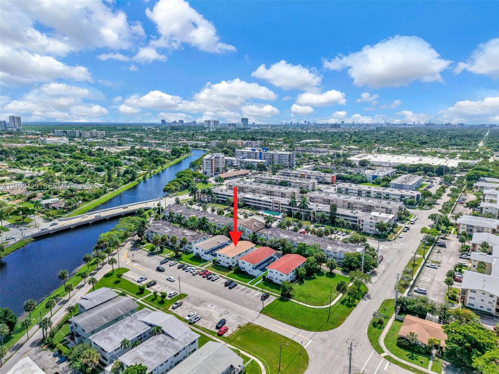 1430 NE 171st Street, North Miami Beach, FL 33162 Aerial perspective of the residential complex featuring multi-story structures, integrated parking areas, manicured green space, and proximity to a waterway
