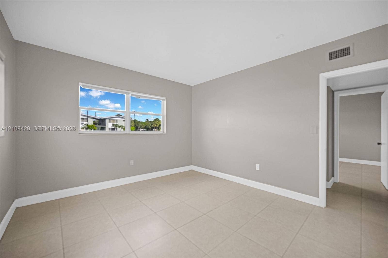 1430 NE 171st Street, North Miami Beach, FL 33162 Neutral-toned interior featuring large-format ceramic tile flooring, soft grey wall finishes, and a dual-pane horizontal sliding window