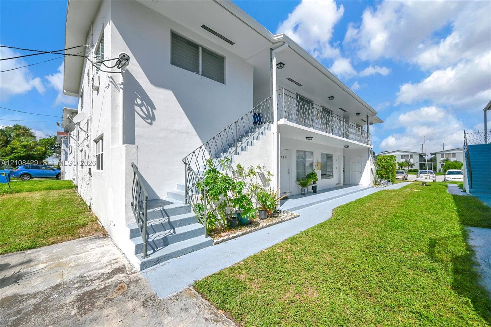 1430 NE 171st Street, North Miami Beach, FL 33162 Two-story exterior featuring a smooth stucco facade, metal railing, exterior staircase, and a covered balcony