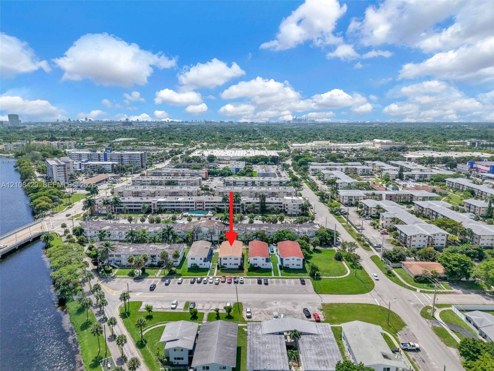 1430 NE 171st Street, North Miami Beach, FL 33162 Aerial perspective of multi-family property featuring a terracotta-toned roof, surface parking, and proximity to the waterfront