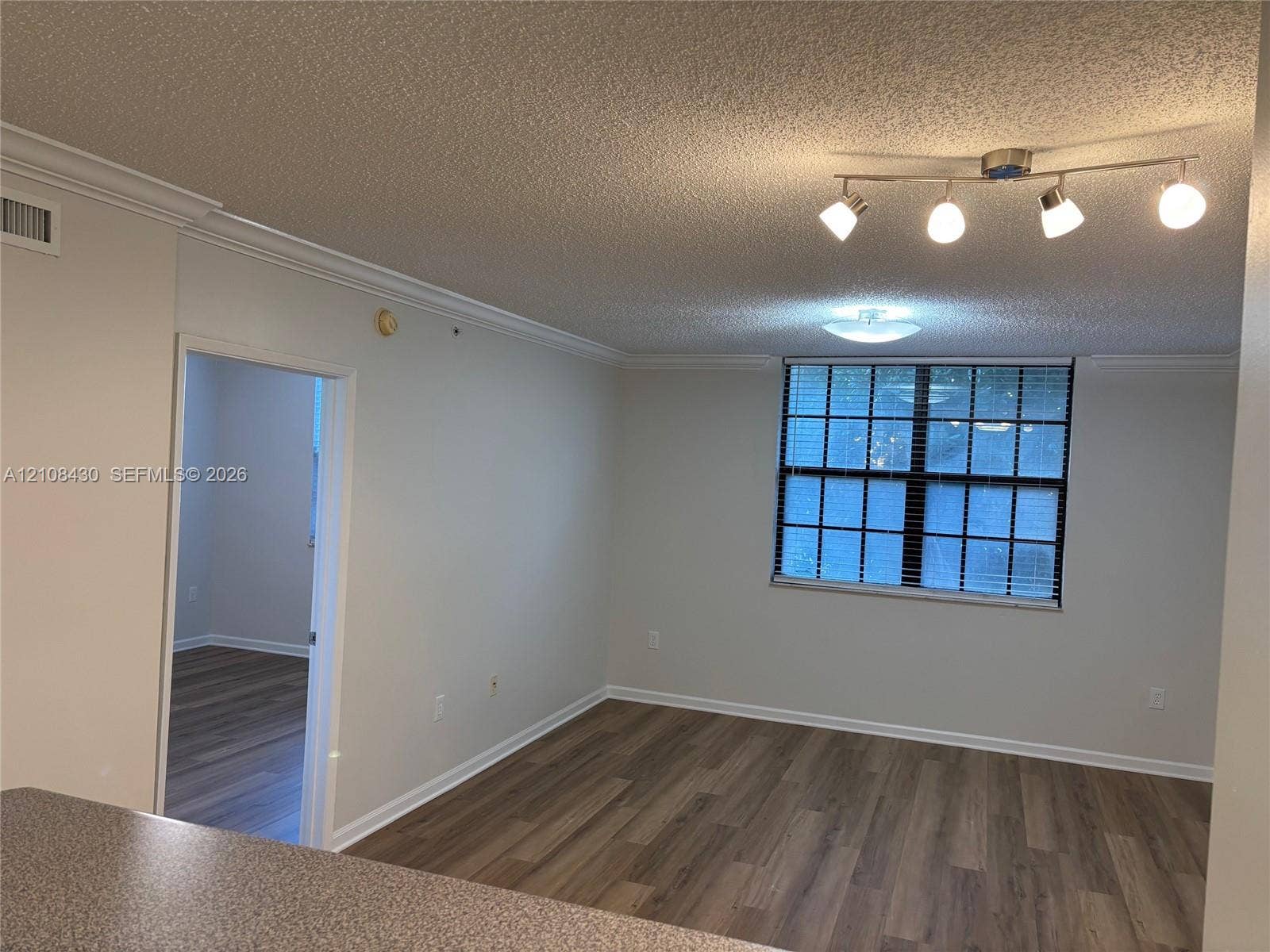 1919 Van Buren Street, #219A, Hollywood, FL 33020 Living area featuring wood-finish flooring, crown molding, multi-bulb adjustable track lighting, and a multi-pane window