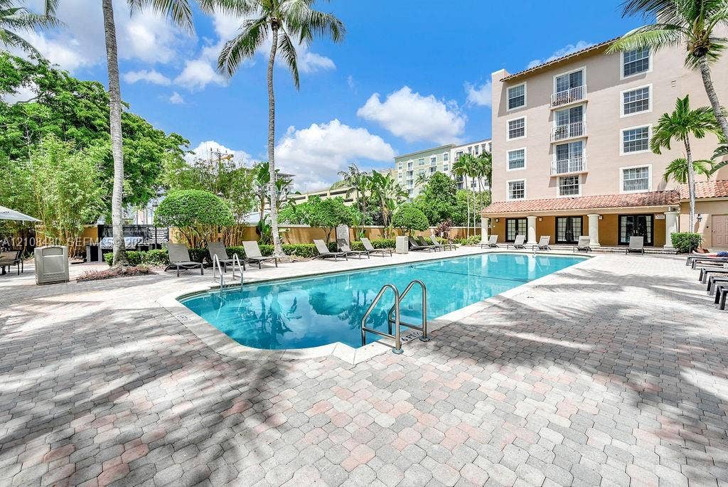 1919 Van Buren Street, #219A, Hollywood, FL 33020 In-ground swimming pool with a stone paver deck, perimeter landscaping, and mature palm trees