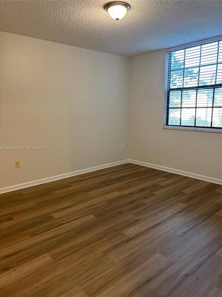 1919 Van Buren Street, #219A, Hollywood, FL 33020 Room featuring wood-finish flooring, a multi-pane window with installed blinds, and a flush-mount ceiling fixture