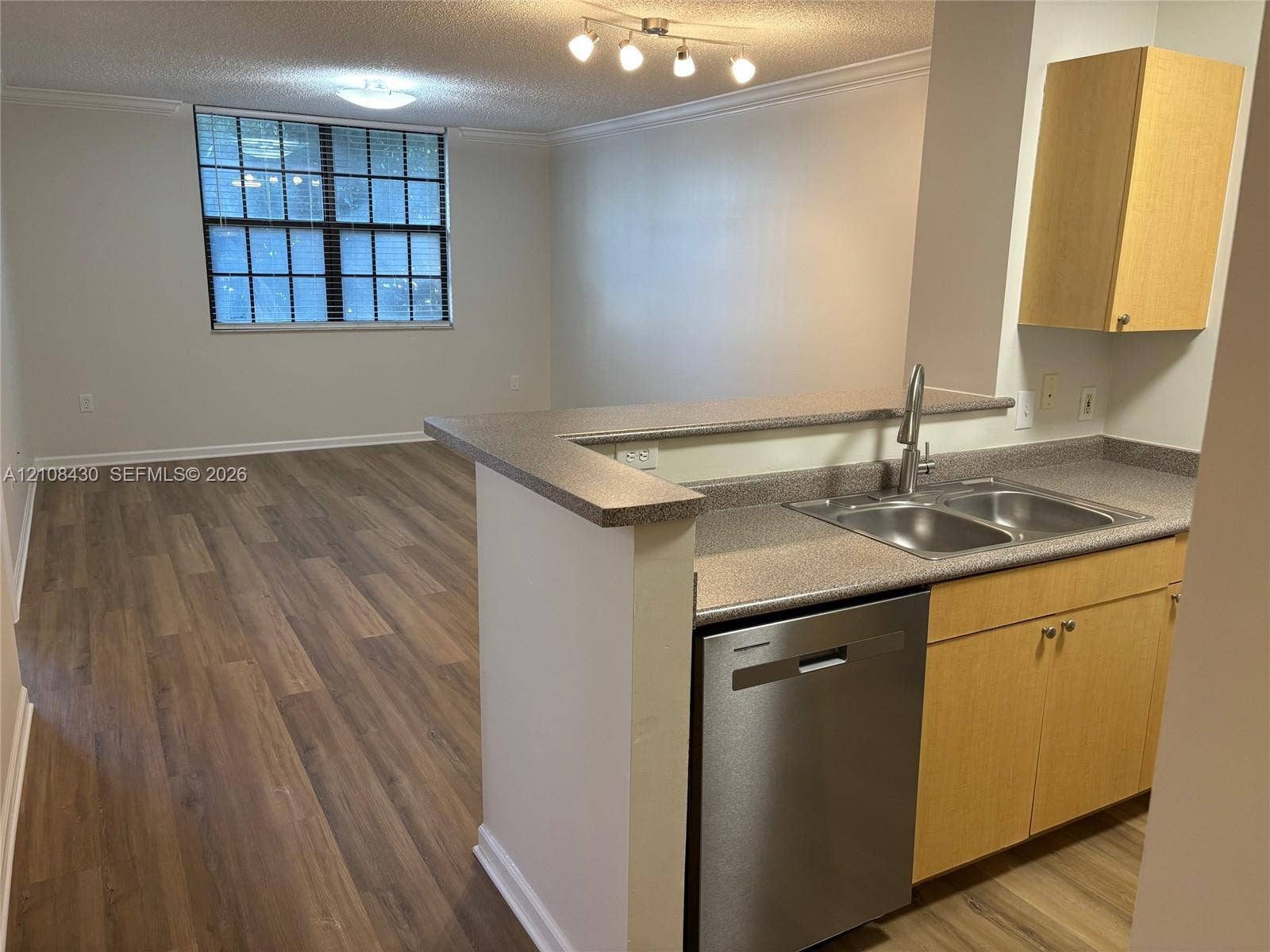 1919 Van Buren Street, #219A, Hollywood, FL 33020 Kitchen featuring light wood-finish cabinetry, solid-surface countertops, dual-basin stainless steel sink, stainless steel dishwasher, and wood-finish flooring