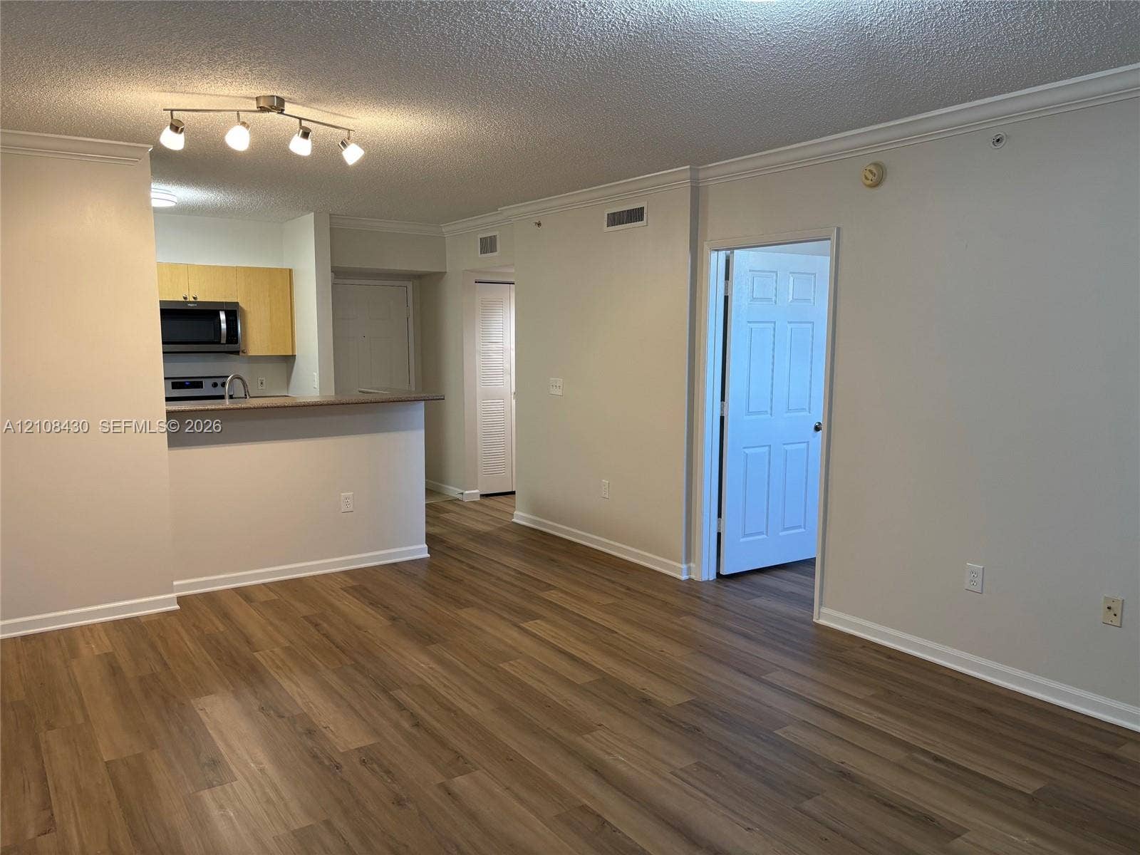 1919 Van Buren Street, #219A, Hollywood, FL 33020 Wood-finish flooring, kitchen with peninsula, built-in microwave, multi-light track fixture, and six-panel interior doors