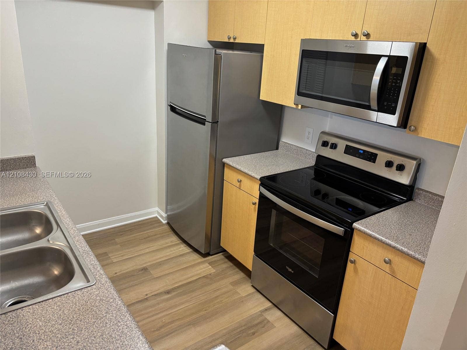 1919 Van Buren Street, #219A, Hollywood, FL 33020 Kitchen featuring wood-finish cabinetry, stone-texture countertops, stainless steel appliances, and wood-finish flooring