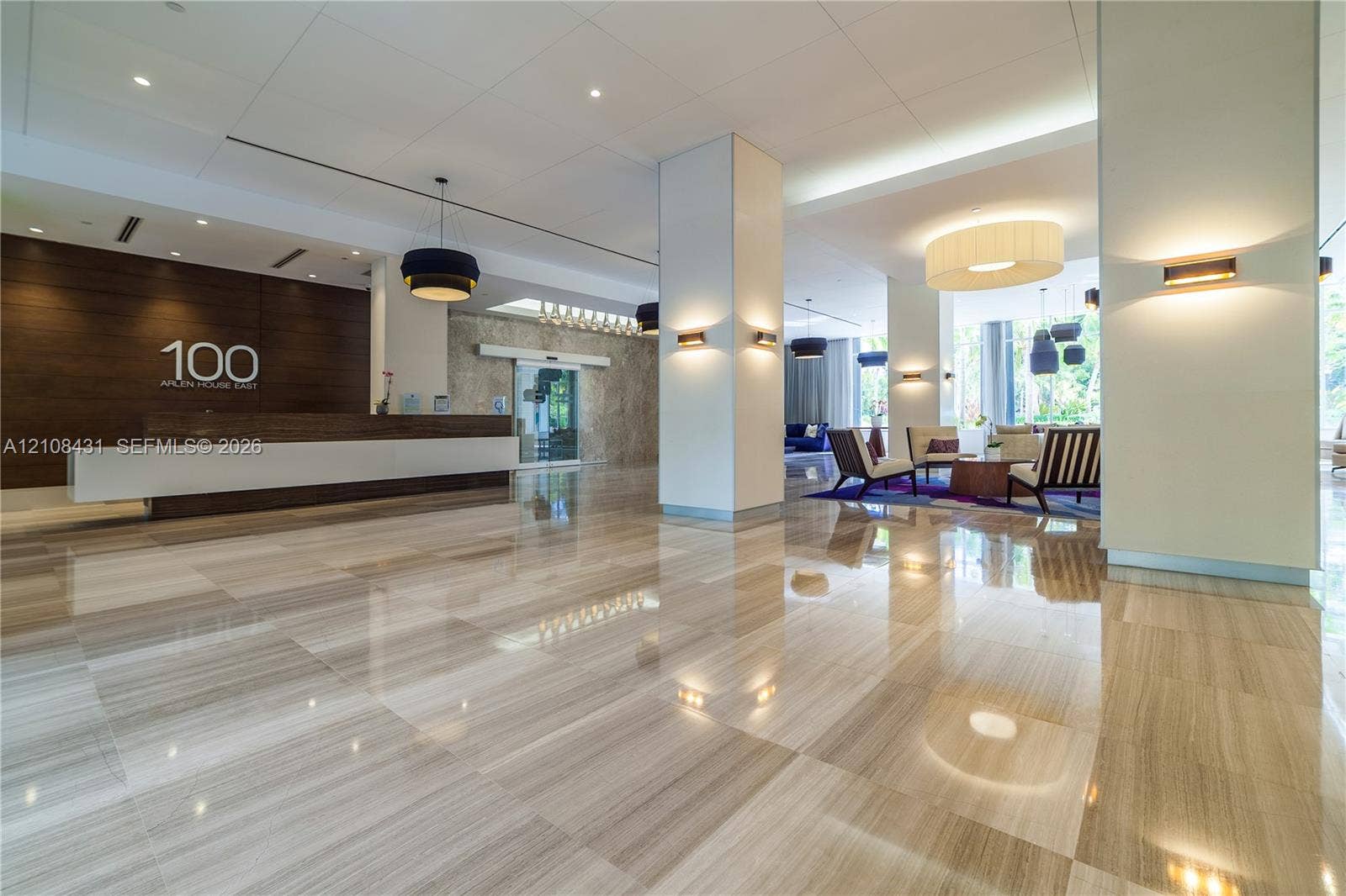 100 Bayview Drive, #1904, Sunny Isles Beach, Sunny Isles Beach, FL 33160 Expansive lobby featuring polished stone flooring, wood-paneled reception desk, structured support columns, and layered architectural lighting