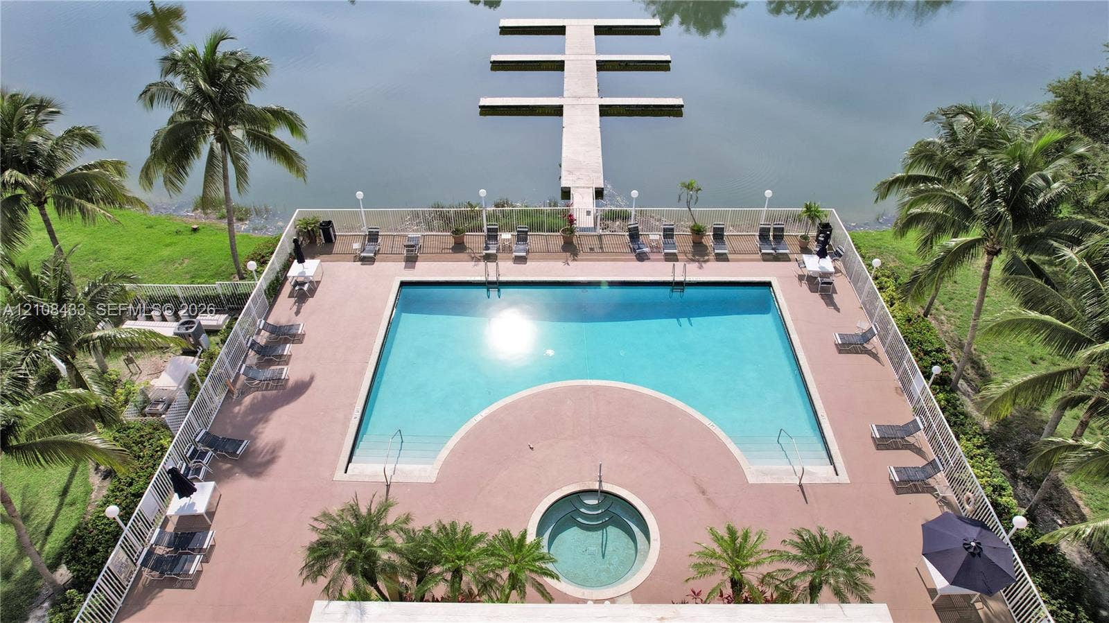 2300 NW 33rd Street, #911, Oakland Park, FL 33309 Waterfront exterior featuring a swimming pool, integrated spa, concrete boat dock, and perimeter fencing