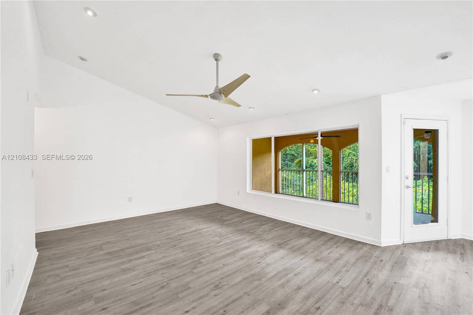 2300 NW 33rd Street, #911, Oakland Park, FL 33309 Vaulted ceilings featuring recessed lighting, wood-finish flooring, a contemporary ceiling fan, and a glass-paneled exterior door