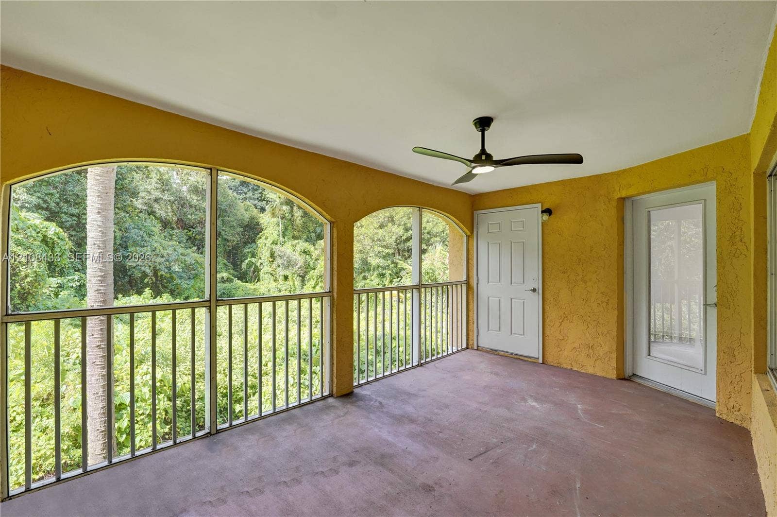 2300 NW 33rd Street, #911, Oakland Park, FL 33309 Covered porch featuring arched screened enclosures, solid surface flooring, and a ceiling fan