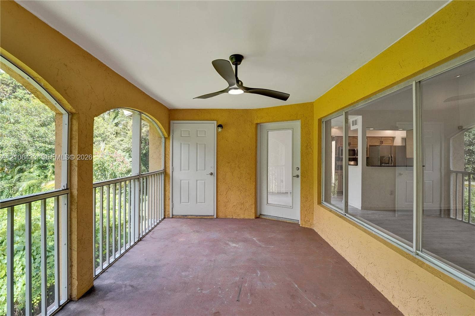 2300 NW 33rd Street, #911, Oakland Park, FL 33309 Covered balcony featuring arched architectural openings, metal railing, concrete flooring, and a ceiling fan with integrated lighting