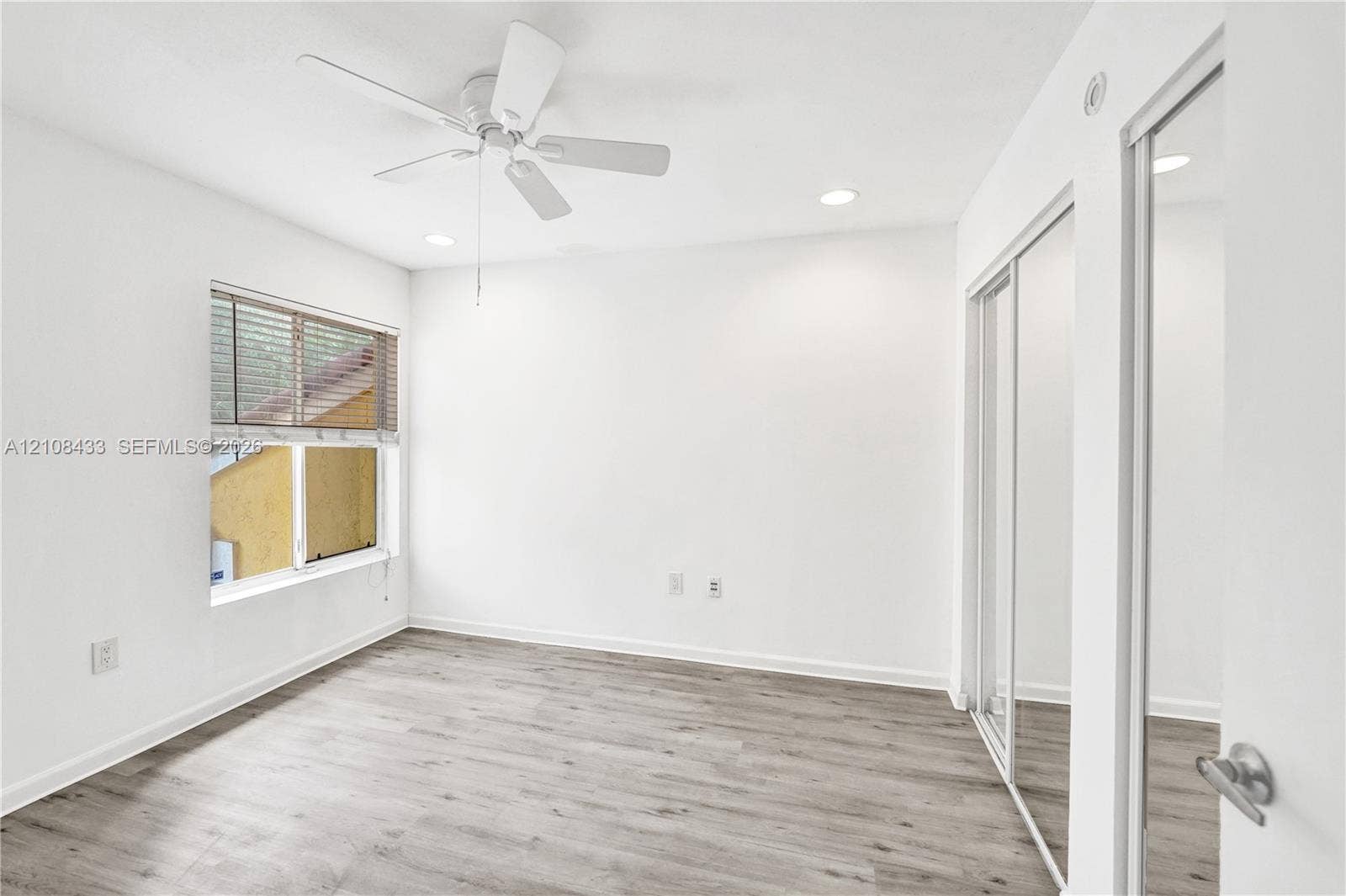2300 NW 33rd Street, #911, Oakland Park, FL 33309 Neutral-toned wood-finish flooring, ceiling fan, recessed lighting, and mirrored sliding closet doors