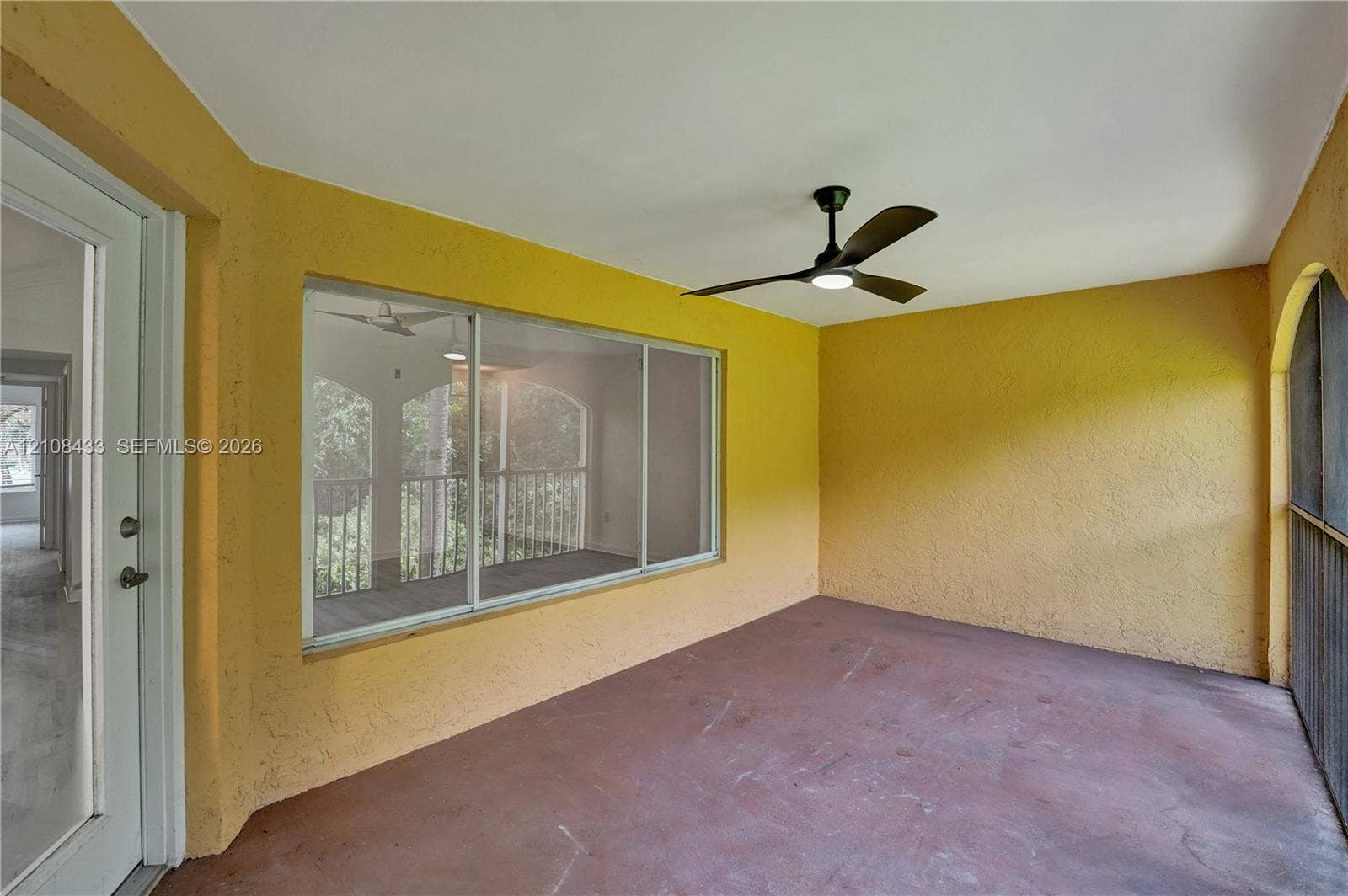 2300 NW 33rd Street, #911, Oakland Park, FL 33309 Covered porch featuring textured walls, concrete flooring, a ceiling fan with integrated lighting, and large sliding windows