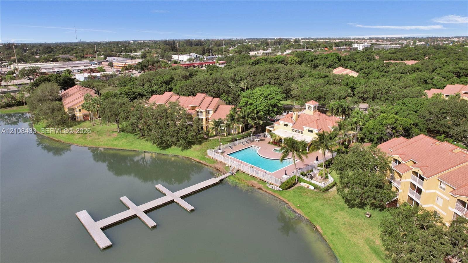 2300 NW 33rd Street, #911, Oakland Park, FL 33309 Aerial perspective featuring multi-story structures with tile roofing, an inground swimming pool, and a private dock extending into the lakefront